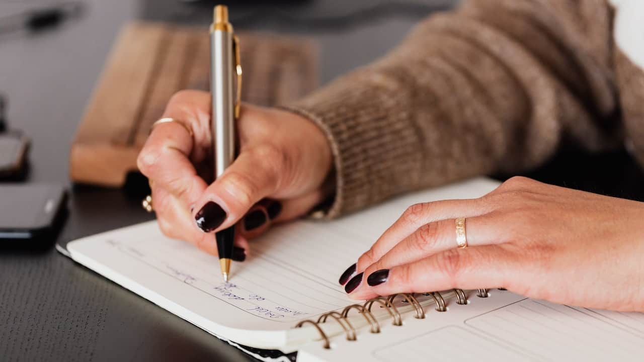 Riciclo delle penne finite, una donna scrive su un quaderno con una penna pressoché esausta