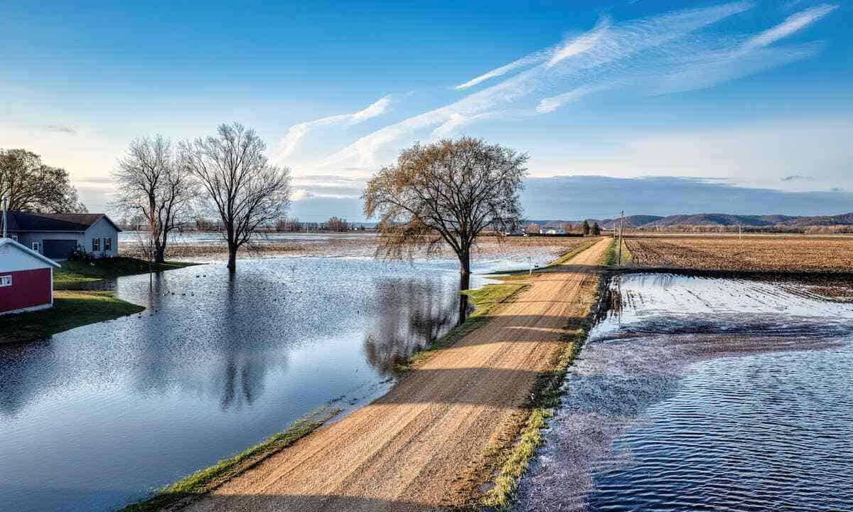 Prevenire alluvioni: una strada di campagna con i campi che costeggia completamente allagati