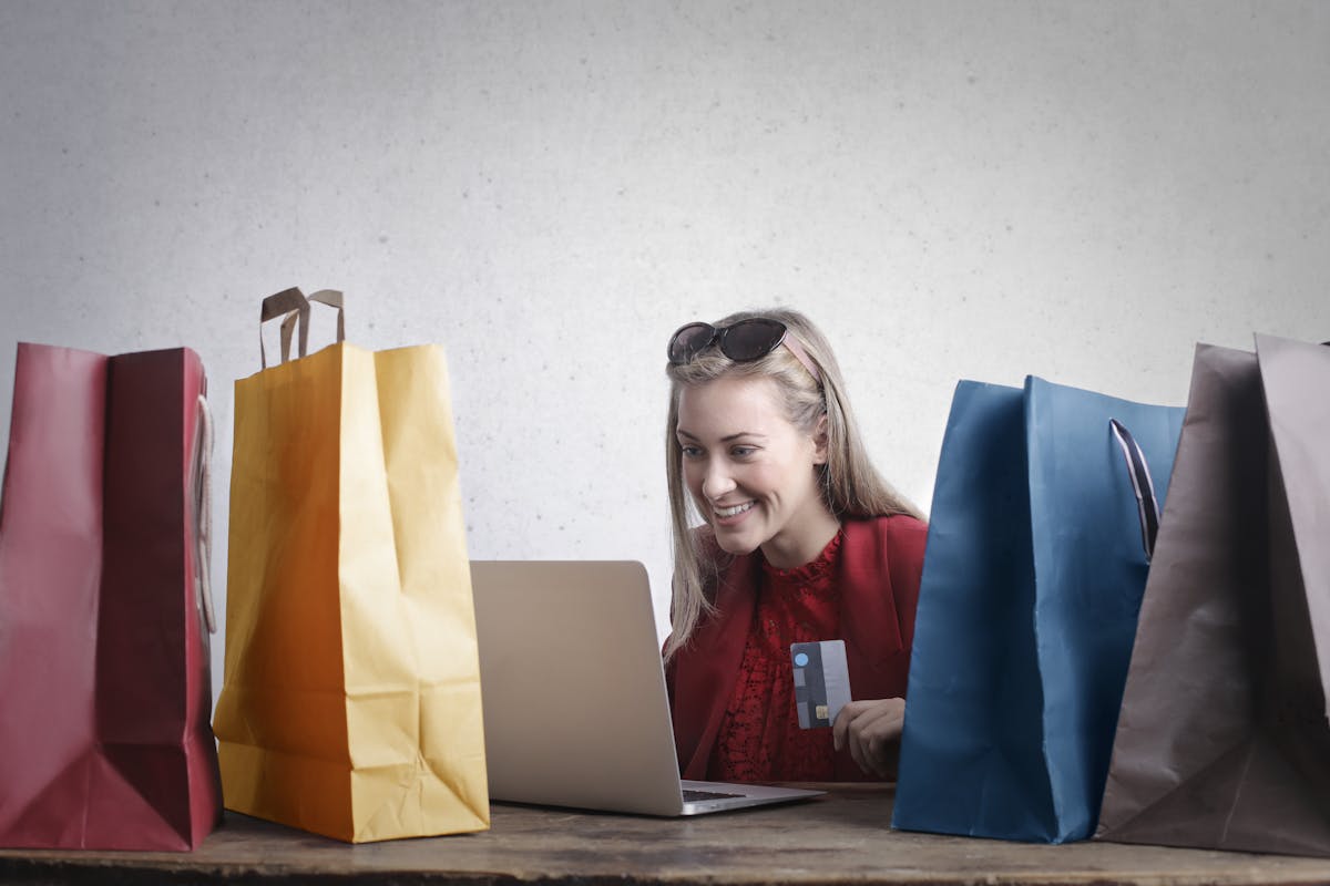 Amazon Haul: una donna di fronte al computer sorridente e colma di pacchi appena acquistati